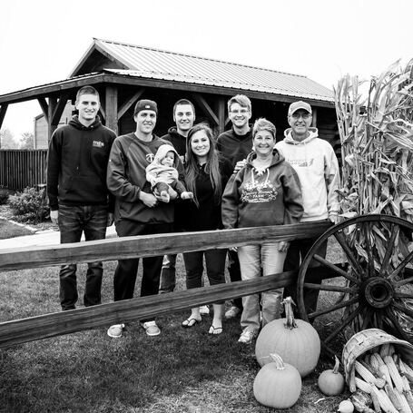 The Evergreen Park family standing at a wooden fence in front of the farm building