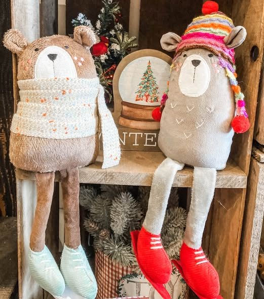 Plush bear figures in knit scarves on a wooden shelf