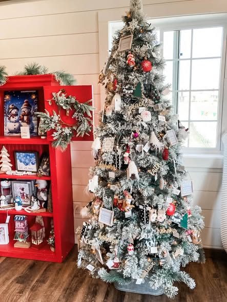 A decorated flocked tree inside the gift shop beside a red display shelf