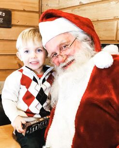 A young boy sitting with Santa Claus inside the Evergreen Park shop